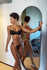 Black padded bra with floral lace and matching thong, modeled by a woman.